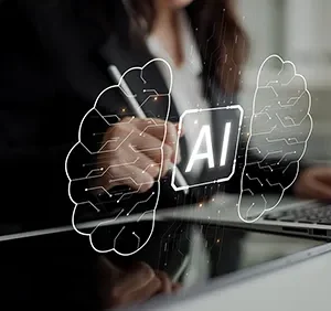 Symbolbild KI im UX/UI Design: Person arbeitet mit Stift und Laptop, davor leuchtet ein Chip mit „AI“ zwischen zwei Gehirnhälften