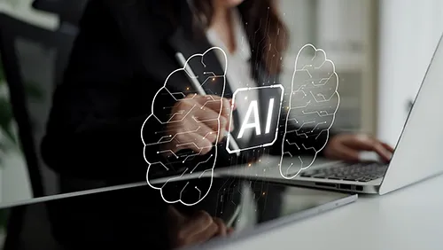 Symbolbild KI im UX/UI Design: Person arbeitet mit Stift und Laptop, davor leuchtet ein Chip mit „AI“ zwischen zwei Gehirnhälften